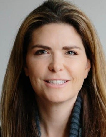 Stephanie is smiling against a light gray background. She is wearing a gray cowl-neck sweater